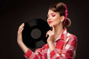 Young beautiful woman with a beautiful hairstyle and bright makeup. She is holding a vinyl  music record. Professional makeup and facial care.