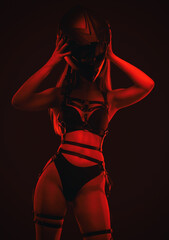 A young slim girl in sexy lingerie holds a black motorcycle helmet on a red lights.