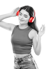 A beautiful young girl in a T-shirt listens to music on red headphones.