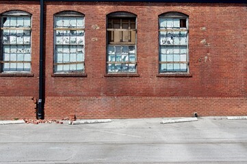 Fototapeta na wymiar Abandoned brick industrial building with broken and weather worn windows