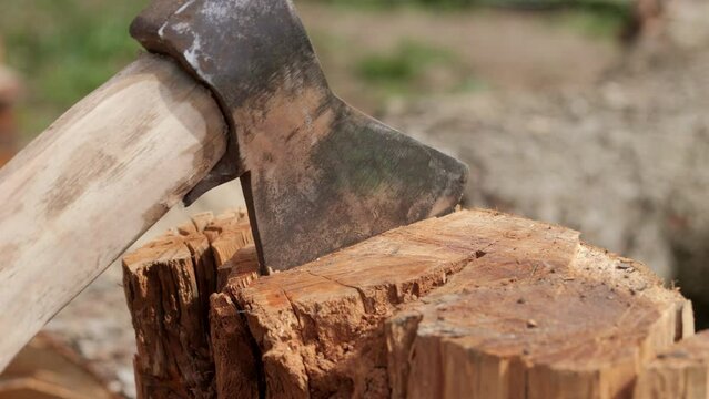 Chopped wood logs with an axe. An ax gets stuck in a log