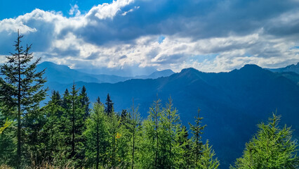 Hiking path in forest with panoramic view of Karawanks mountain range on sunny day in Carinthia,...
