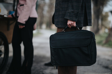 Detail shot of a businessperson's hand carrying a black briefcase, suggesting professionalism and partnership.