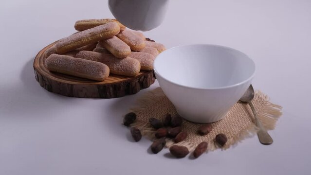 Versare la cioccolata nella tazza, colazione con i biscotti, tagliere con i biscotti, fave di cioccolato sul tavolo 