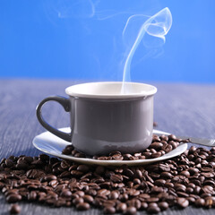 Obraz premium Tazza di caffè fumante sul piattino con chicchi di caffè