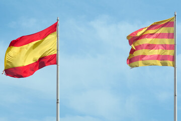 The image shows the flags of Catalonia and Spain waving together in a clear sky, symbolizing coexistence and mutual respect between both identities.