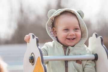 A beautiful, cheerful little boy of two years old walks on the playground in the spring. The...