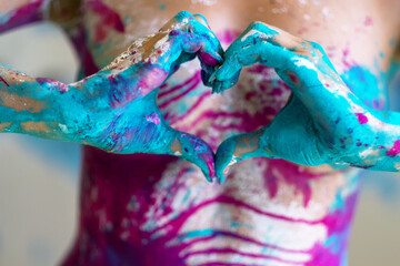 colored hands of sexy young nude woman, form shape a heart in turquoise and white color painted decorative. Creative expressive abstract body painting art