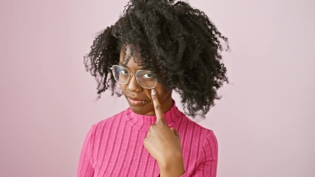 Confident african american woman stands, pointed finger on her glasses. spy-like, she's watching you with a serious look, expressing suspicion.