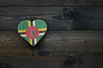wooden heart with national flag of dominica on the wooden background.