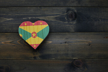 wooden heart with national flag of grenada on the wooden background.