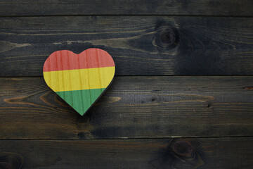 wooden heart with national flag of bolivia on the wooden background.
