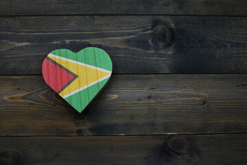 wooden heart with national flag of guyana on the wooden background.