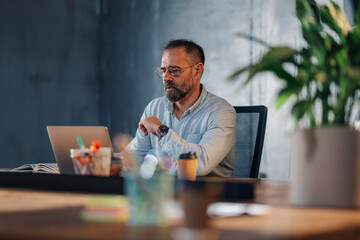 CEO sitting at modern workspace and working on a project on a laptop.