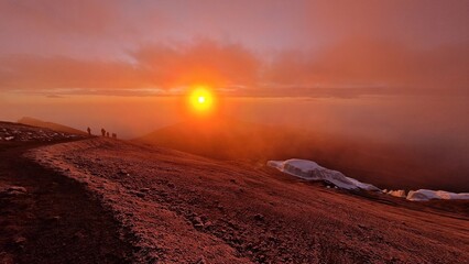 Bergsteiger erklimmen den Gipfel des Kilimanjaro im Morgengrauen bei aufgehender Sonne im...