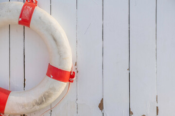 Aged life ring on white wooden background.