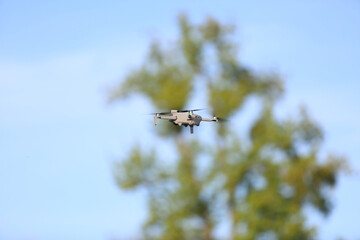 Dron w locie, w powietrzu na tle korony zielonego drzewa. © Stanisław Błachowicz