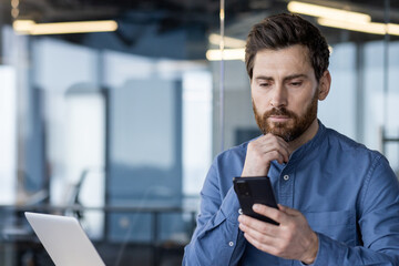 Focused businessman using smartphone in the office