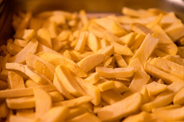 Yummy French fries  as background. Potato chips on the counter at the street market. Selective focus. Side view. Bokeh.