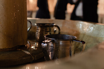 Cranes with water and a special ritual cups for washing hands near Western Wall, an important jewish religious site Jerusalem. Israel. Copper Pots for ritual Ablution in front of the Wailing Wall.