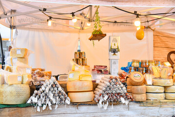 Naklejka premium Market stall of farmer's market with cheeses, sausages and vergine olive oil