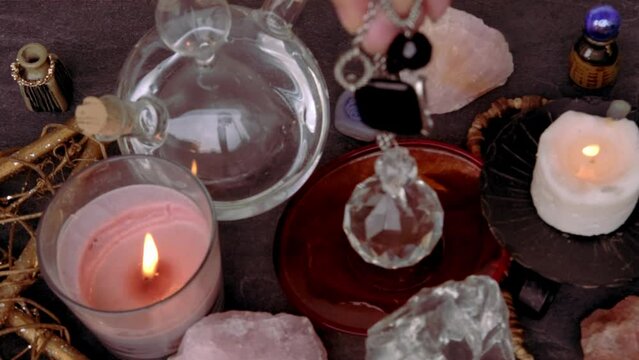 female hand holding and using glass ball crystal ball, pendulum swings over astrologer's table, Harmony with meditation, self-discovery, Spiritual Energy and Balance, divination and fortune-telling