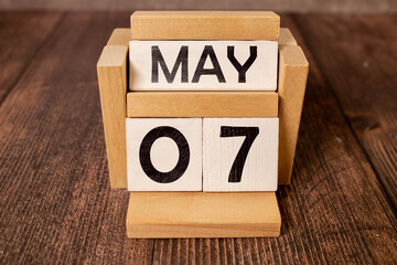 7 Mai on wooden grey cubes. Calendar cube date 07 May. Concept of date.