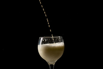 Fillet of milk with drops falling from above into a glass wine glass.