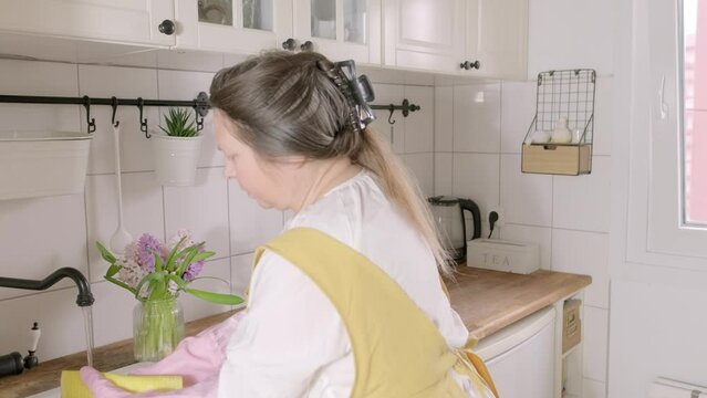 woman in yellow apron diligently cleans spotless white kitchen, spring home cleaning, conveying joy of maintaining clean and organized home environment, capabilities of plus-size individuals