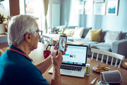 Elderly man in telehealth session with doctor on smartphone at home
