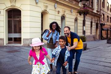 Joyful diverse family having fun on a city walk - obrazy, fototapety, plakaty