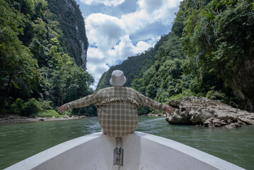 A woman enjoys a trip along a river that cuts through a tropical rainforest