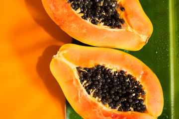 Exotic fruits background. Papaya orange fresh fruits on tropical leaf green background. Halved fresh organic Papayas exotic fruits close up Top view, border design - 779245615