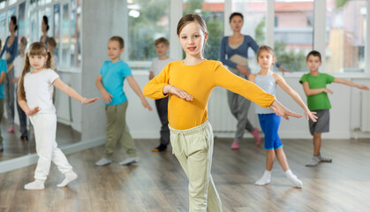 During dance workshop, girl with team of young like-minded children learn to dance hip hop dances,...