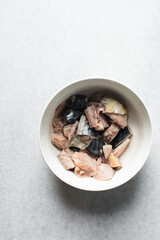 Overhead view of chopped raw mackerel fish in a white bowl, chunks of scomber fish in white ceramic...