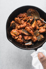 Overhead view of Sauteed spicy mackerel in a cast iron skillet, top view of chili fish chunks