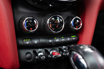 The dashboard of a car has a red trim and three buttons on it. The buttons are labeled with the letters A, B, and C