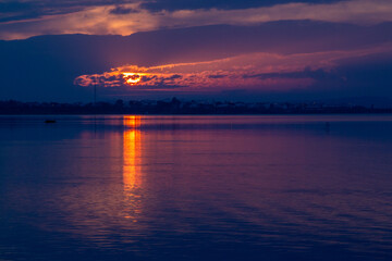 Sunset over the sea with dramatic sky and reflection in the water. Beautiful sunset on the lake in the evening. Nature composition.