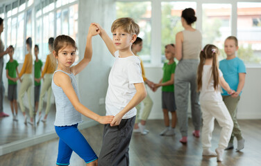 Fototapeta premium Preteen children learn to dance tango under guidance of a teacher in the ballroom
