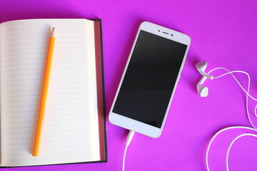 a white phone is open to a notebook with a pen on it.