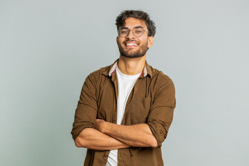 Cheerful lovely happy young Indian man smiling friendly glad expression looking at camera dreaming resting relaxation feel satisfied good news. Arabian bearded guy isolated on gray studio background
