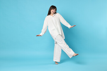 Happy woman wearing pyjama on light blue background