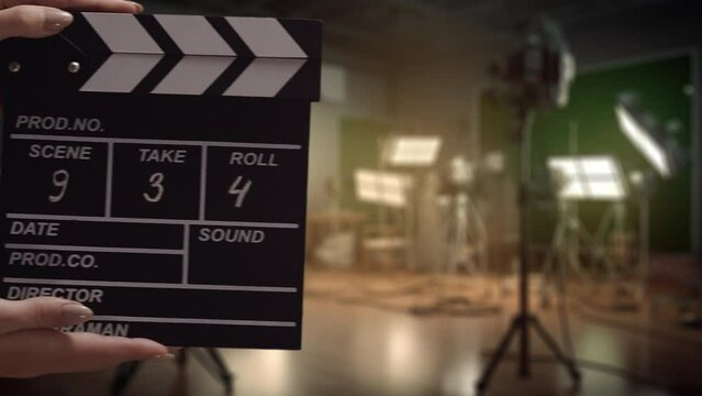 Human hands are using a clapperboard on set. Beginning of scene in film or TV television production. Concept of cinematography movie or video crew. Stage and filmmaking equipment background