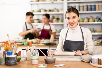 Fototapeta premium Young woman in apron modeling clay pottery in workshop