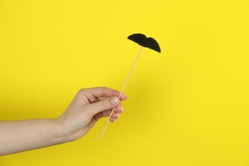 Woman with fake paper mustache on yellow background, closeup