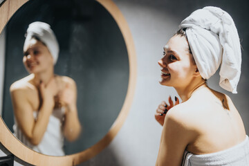A serene woman wrapped in a towel enjoys a moment of tranquility after a shower, reflecting in a...