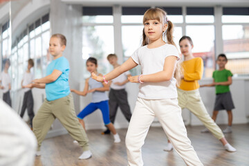 Happy positive smiling preteen boys and girls practicing dance, with female trainer in dance hall