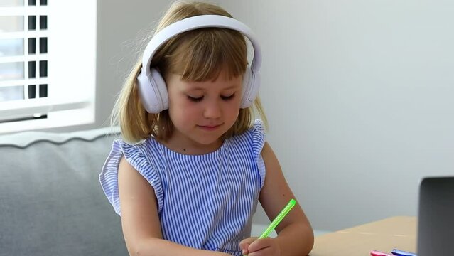 Schoolgirl with earphones draws listening to video lesson