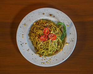 Pesto spaghetti garnished with tomatoes and pine nuts
