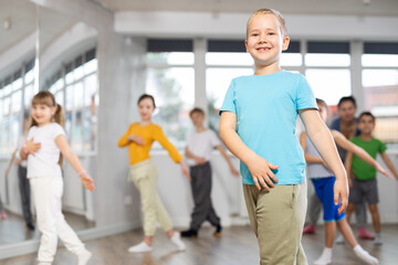 Happy positive smiling preteen boys and girls practicing dance, with female trainer in dance hall